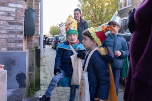 Drie kinderen verkleed met mijter wachtend aan een deur