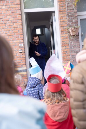 Meneer doet de deur open voor zingende kinderen