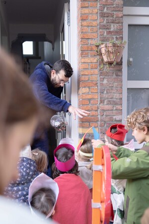 Meneer doet de deur open voor zingende kinderen