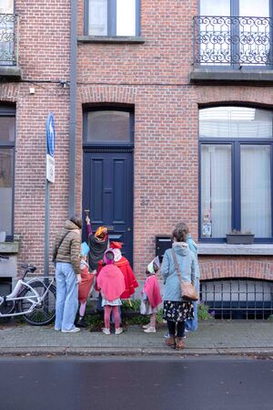 Drie kinderen verkleed met mijter en mantel wachten voor een deur