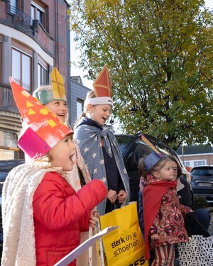 Vier zingende kinderen verkleed met mantel en mijter