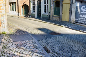 Deze tegels met de afdrukken van vallende druppels (verschillende cirkels) staan symbool voor een vlietje dat onder de straat door loopt.